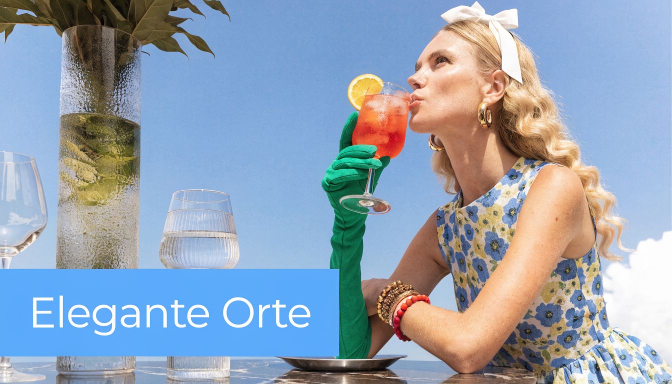 Eine elegante Frau mit grünen Handschuhen trinkt einen Spritz bei sonnigem Wetter an einem luxuriösen Tisch.