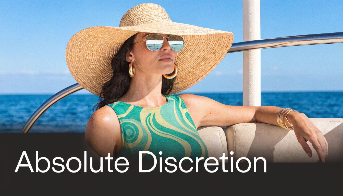 Eine elegante Frau mit Sonnenhut und Sonnenbrille entspannt auf einer luxuriösen Yacht vor dem blauen Meer.